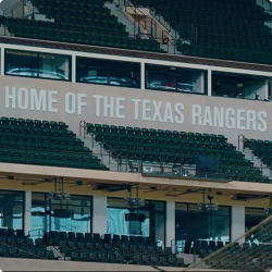 Photograph of stadium seats with 'Home of the Texas Rangers" above them